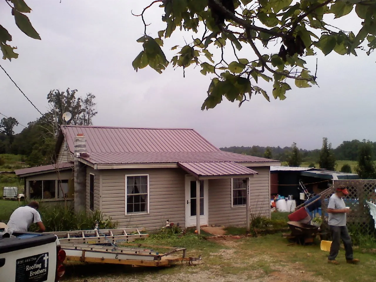 Crew finishing a mauve metal roof on a small farmhouse in Lucernemines