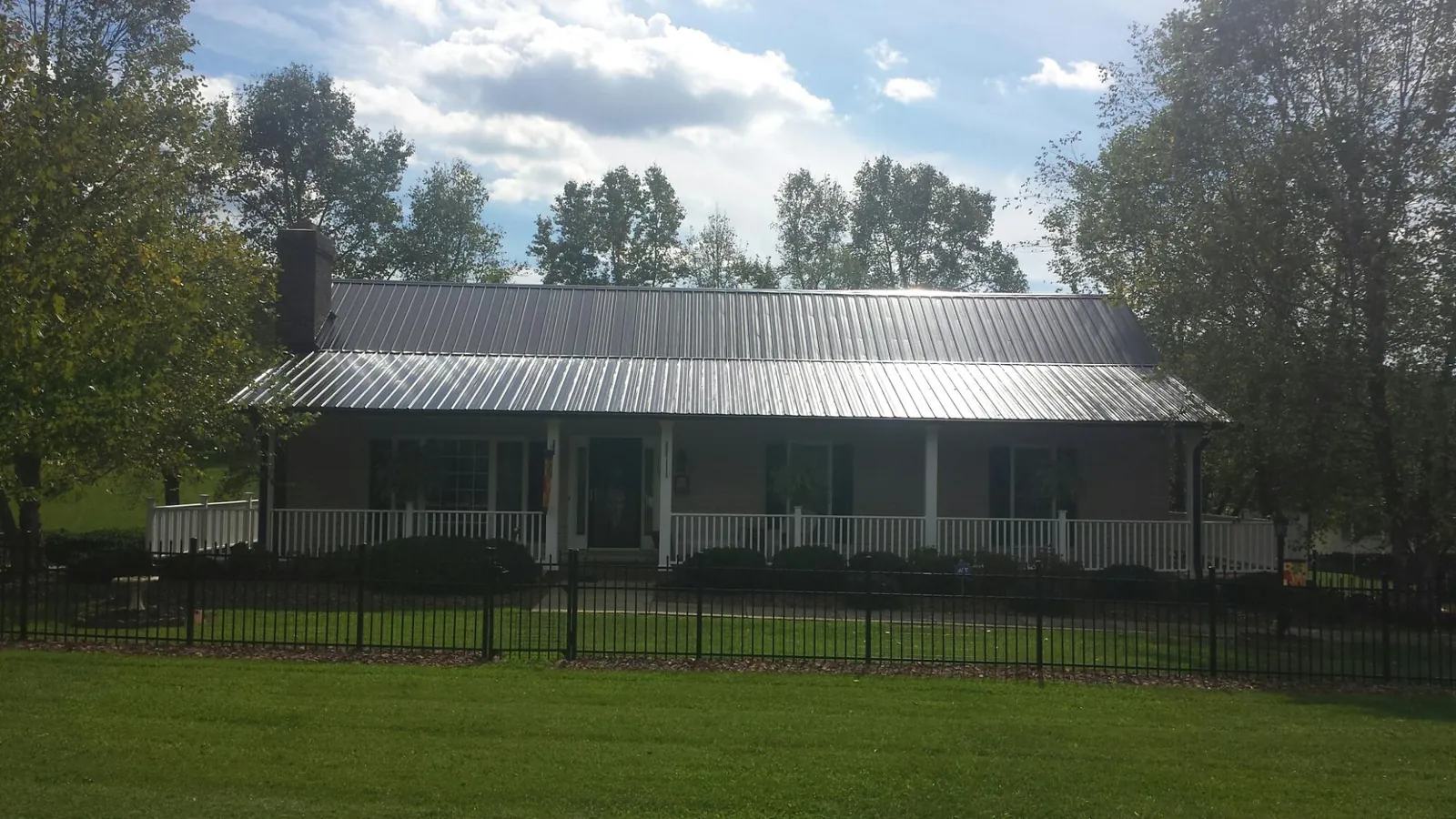 Gray metal roof on a brick ranch with a full width front porch — Gutter Guard Installation work by our crew in Lucernemines