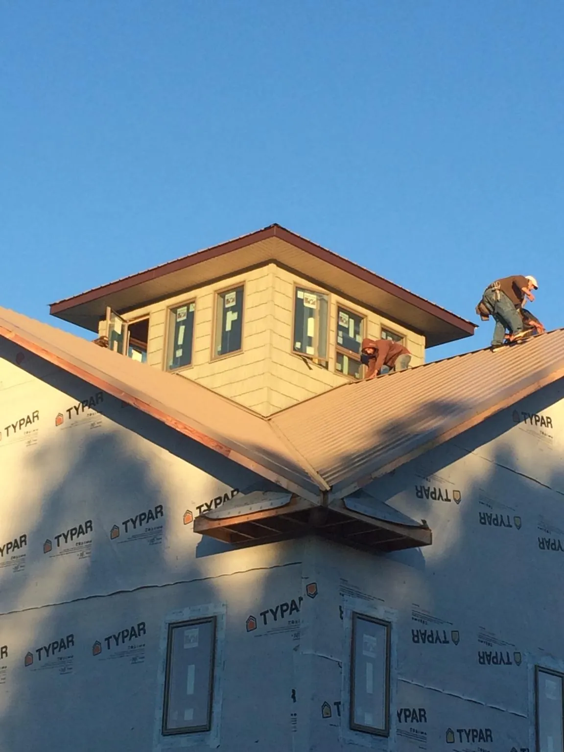Roofers working around a rooftop cupola on a new metal roof at sunset — Roof Waterproofing in Lucernemines by Roofing Brothers
